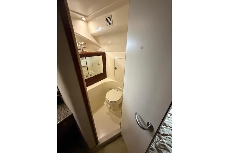 Slide: The Image of 2004 Sea Ray 480 Sedan Bridge bathroom with toilet, mirror, and compact design. - 44