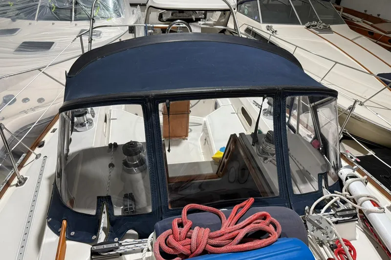 Slide: The Image of 1986 Sabre 34 MK II sailboat with blue canopy and ropes, docked among other boats. - 3