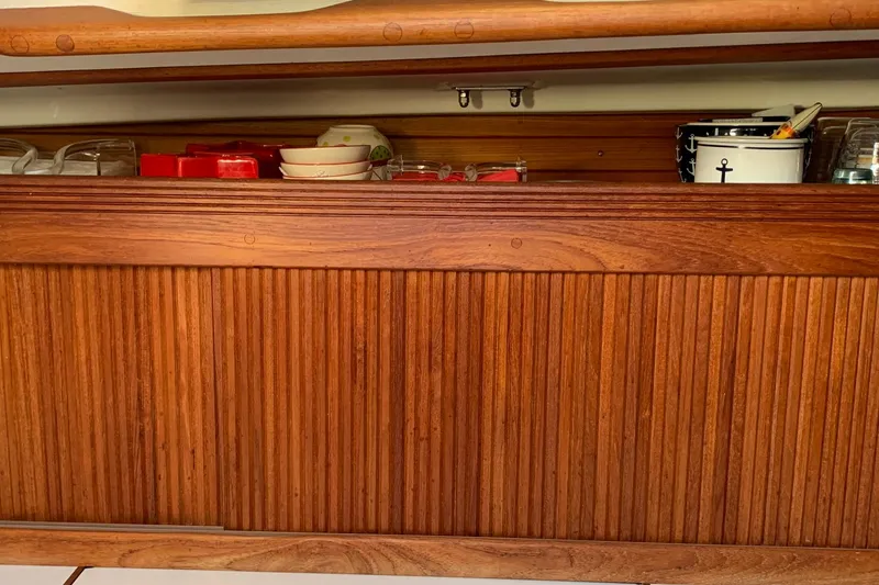Slide: The Image of Wooden cabinet interior on a 1986 Sabre 34 MK II sailboat, storing kitchen items. - 32