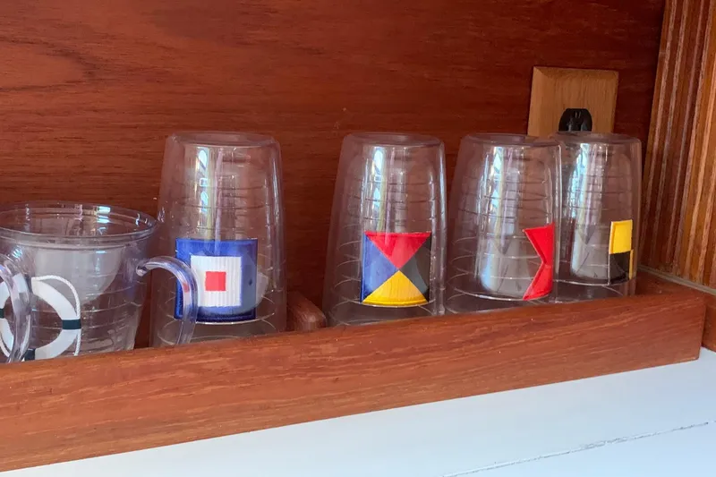 Slide: The Image of Clear plastic cups with nautical flag designs on a wooden shelf. Sabre 34 MK II, 1986. - 33