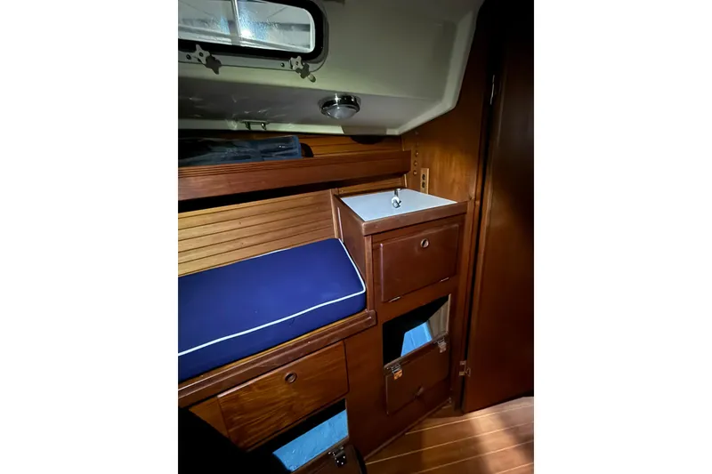 Slide: The Image of 1986 Sabre 34 MK II yacht interior with wooden cabinetry and blue cushioned seating. - 51