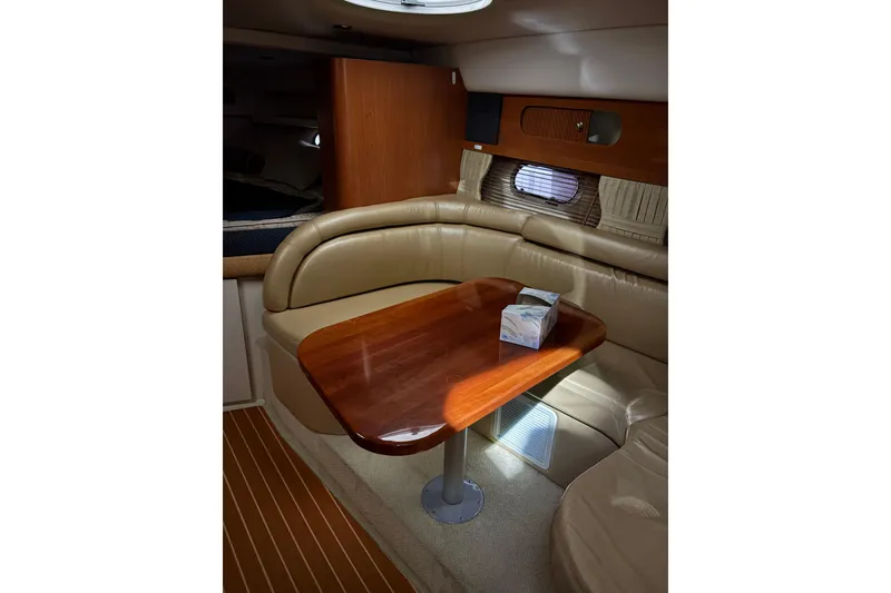 Slide: The Image of 2003 Four Winns 328 Vista cabin interior with wooden table and beige seating. - 14