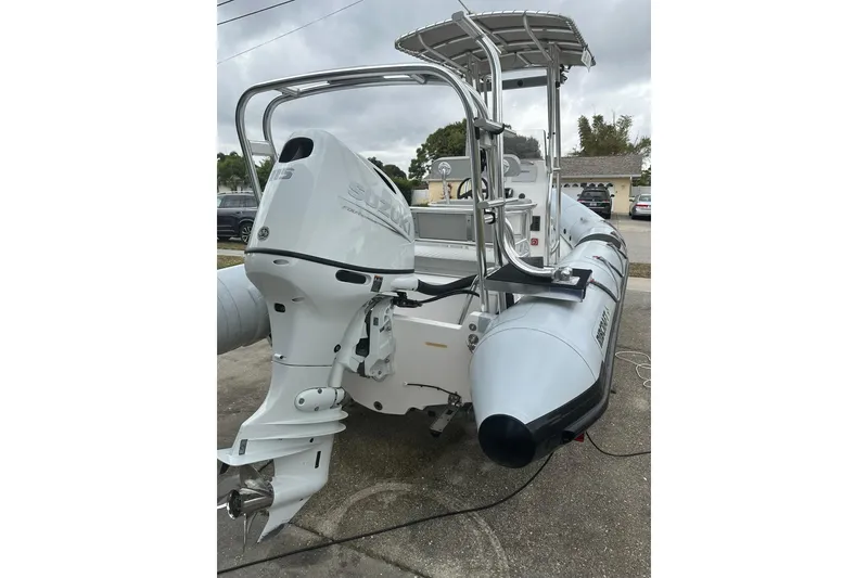 Slide: The Image of 2023 Ribcraft 5.85 boat with Suzuki outboard motor, parked on concrete surface. - 6