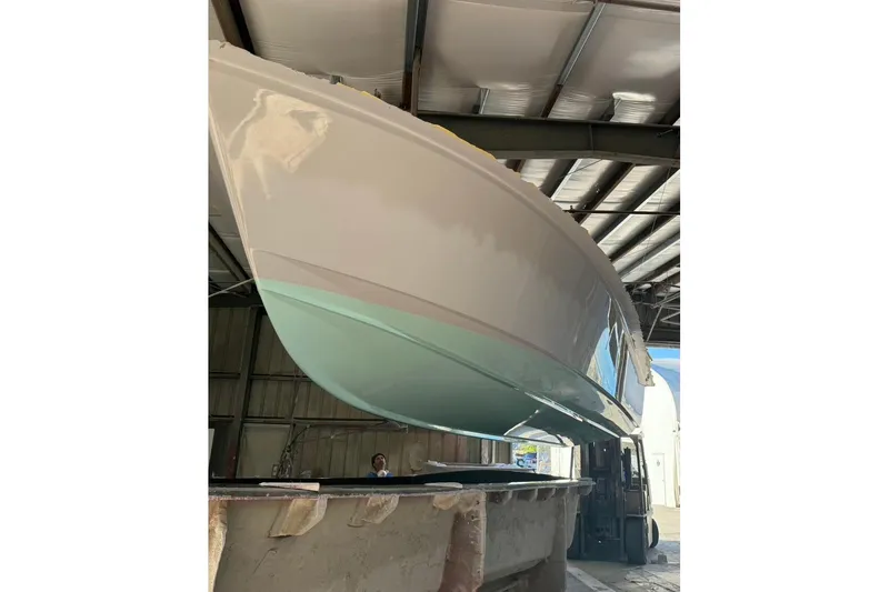 Slide: The Image of 2026 Albury Brothers 23 boat in a workshop, featuring a sleek design with a red stripe. - 0