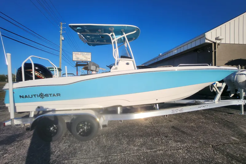 The Image of 2026 NauticStar 231 Hybrid boat on trailer, blue and white design, outdoor display. - 0