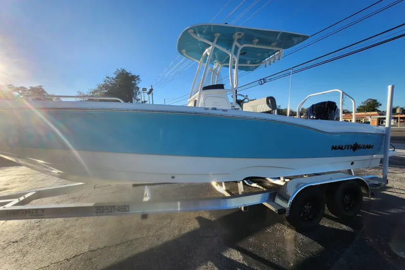 Slide: The Image of 2026 NauticStar 231 Hybrid boat on trailer, blue and white design, sunny day. - 11