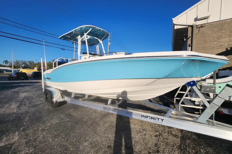 Slide: The Image of 2026 NauticStar 231 Hybrid boat on trailer, blue and white design, parked outdoors. - 12