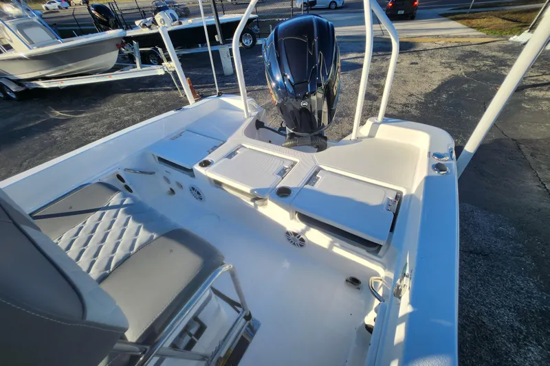 Slide: The Image of 2026 NauticStar 231 Hybrid boat interior with seating and engine, parked outdoors. - 2