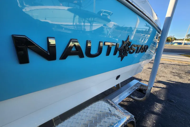 Slide: The Image of 2026 NauticStar 231 Hybrid boat, blue hull with logo, parked on trailer. - 8