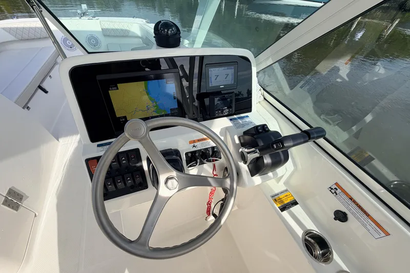 Slide: The Image of 2026 World Cat 230 DC boat dashboard with steering wheel and navigation display. - 12