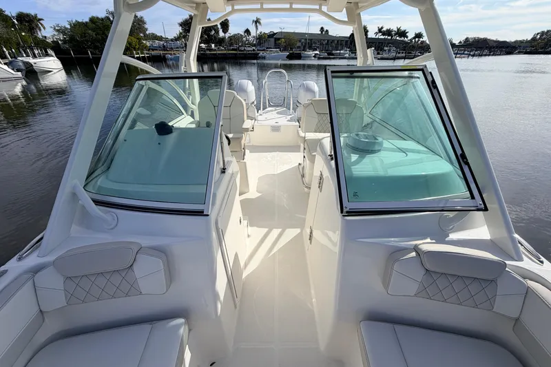 Slide: The Image of 2026 World Cat 230 DC boat interior with seating and windshield, docked on a calm waterway. - 15