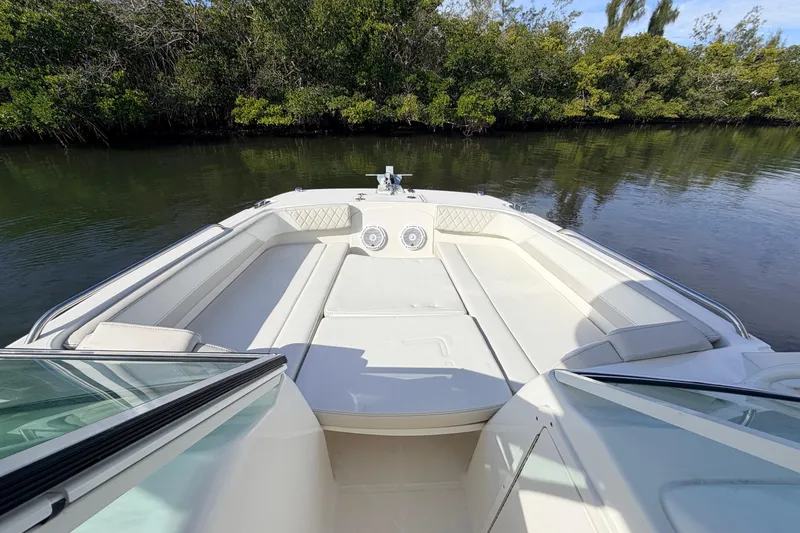 Slide: The Image of 2026 World Cat 230 DC boat interior with white seating, on calm water near lush greenery. - 18