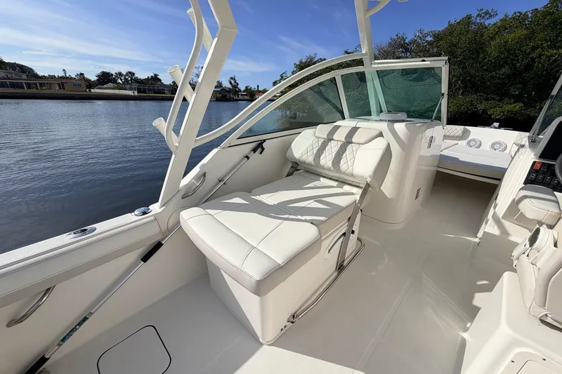 Slide: The Image of 2026 World Cat 230 DC boat interior with white seating, docked by a serene waterway. - 19