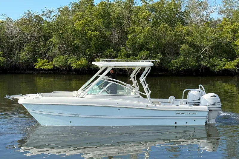 Slide: The Image of 2026 World Cat 230 DC boat on calm water, surrounded by lush greenery. - 5