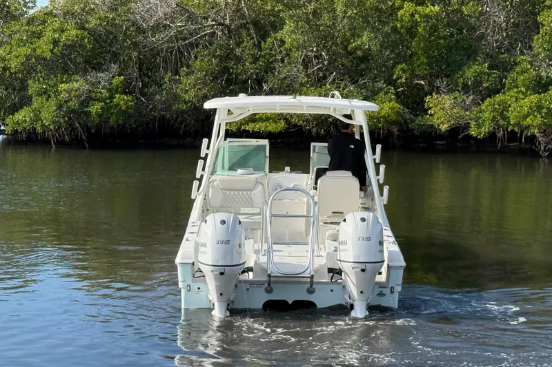 Slide: The Image of 2026 World Cat 230 DC boat navigating through calm waters near lush greenery. - 7