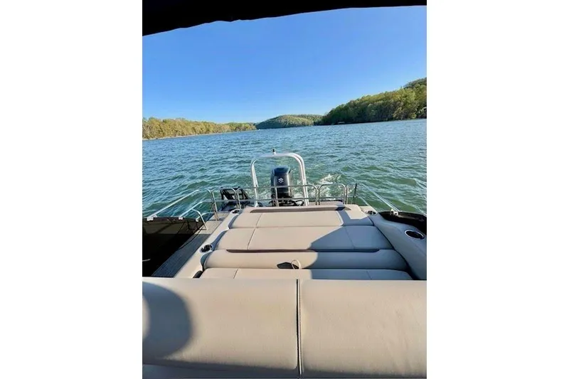 Slide: The Image of 2025 Bentley Pontoons Legacy 243 Swingback on a serene lake with scenic views. - 6