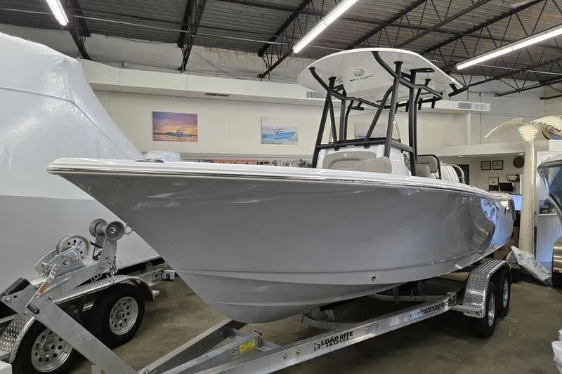 The Image of 2025 Sea Hunt Ultra 229 boat on trailer in showroom setting. - 1
