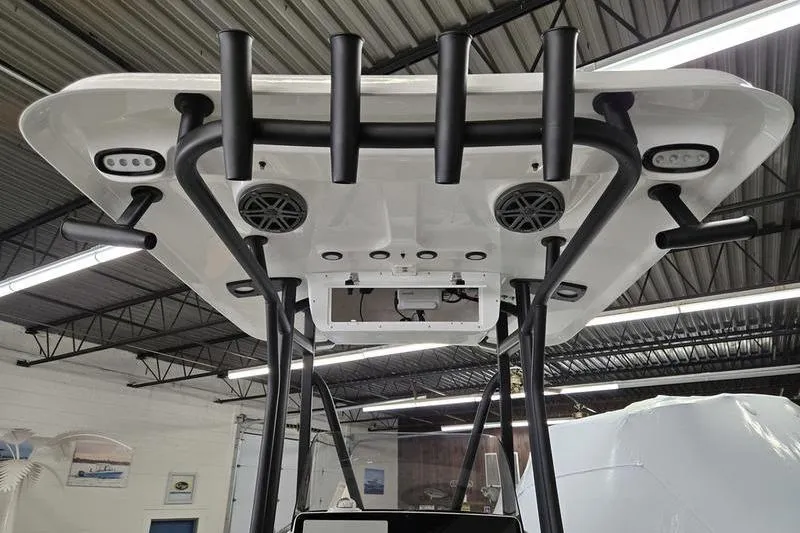 Slide: The Image of 2025 Sea Hunt Ultra 229 boat T-top with rod holders and speakers in a showroom. - 20