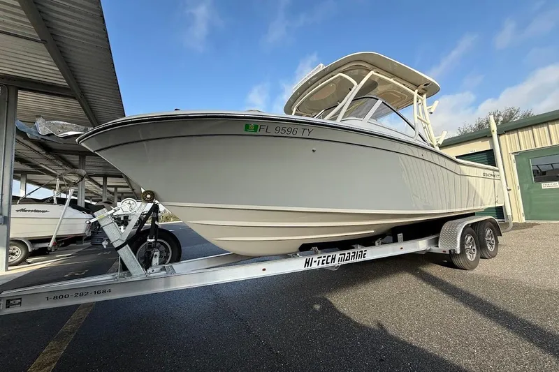 Slide: The Image of 2022 Grady-White Freedom 235 boat on trailer, parked outdoors under a metal canopy. - 48