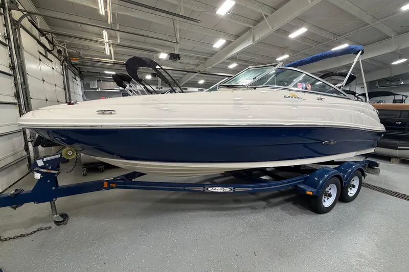 The Image of 2006 Sea Ray 200 Sundeck boat on trailer in indoor storage facility. - 1