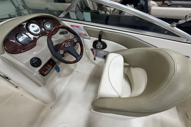 Slide: The Image of 2006 Sea Ray 200 Sundeck helm with steering wheel and gauges, featuring beige seating. - 9