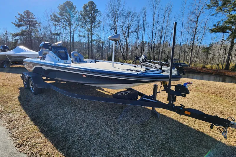 Slide: The Image of 2023 Nitro Z20 boat on trailer, parked on grass near trees and water. - 1