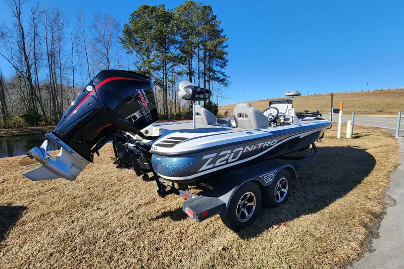 Slide: The Image of 2023 Nitro Z20 boat with powerful outboard motor on a trailer, parked outdoors. - 2