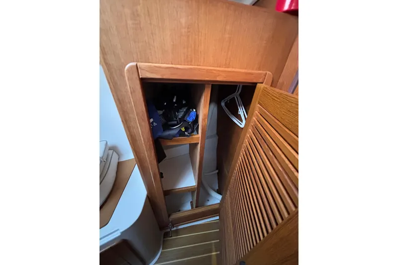 Slide: The Image of Wooden closet interior on a 1999 Catalina 380 sailboat, featuring shelves and hangers. - 41
