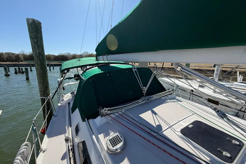 Slide: The Image of 1999 Catalina 380 sailboat docked, featuring green canvas covers and rigging details. - 63