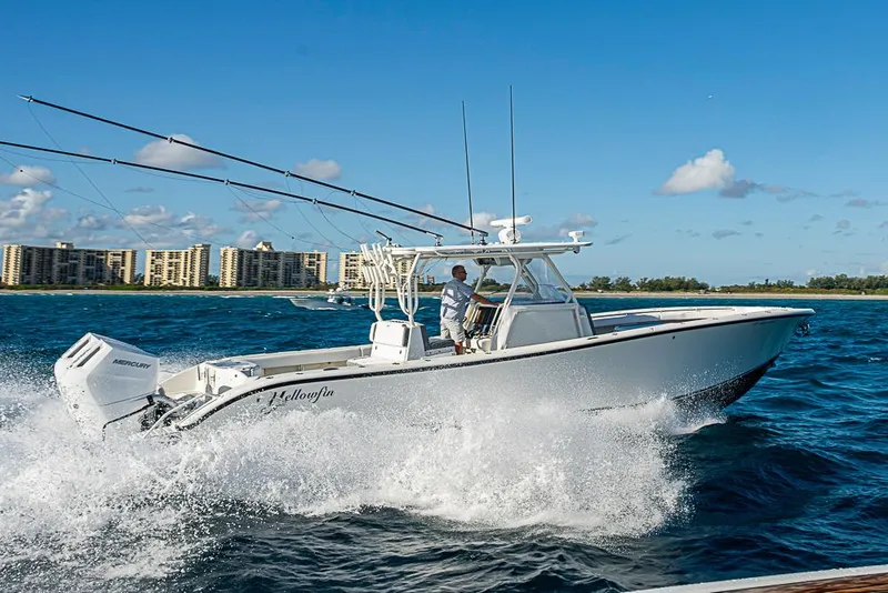 Slide: The Image of 2011 Yellowfin 39 Offshore boat cruising on blue ocean near coastal buildings. - 32