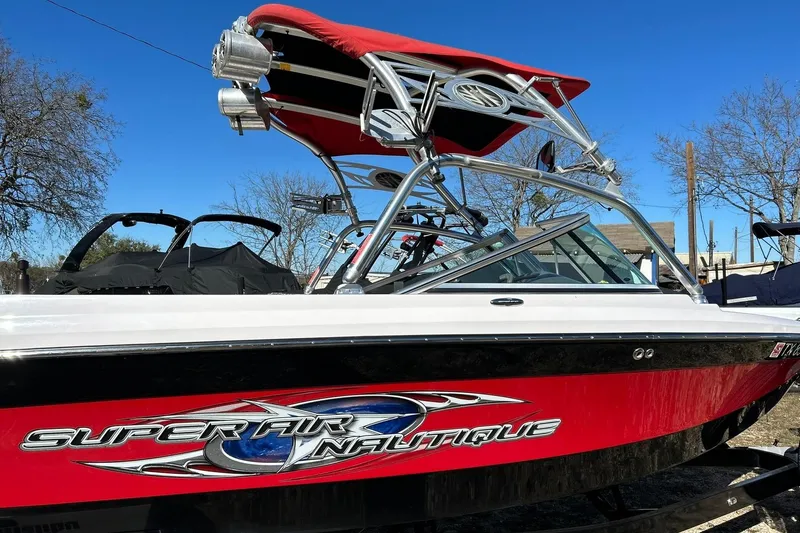 Slide: The Image of 2007 Nautique Super Air Nautique 220 boat with red and white design, parked outdoors. - 14