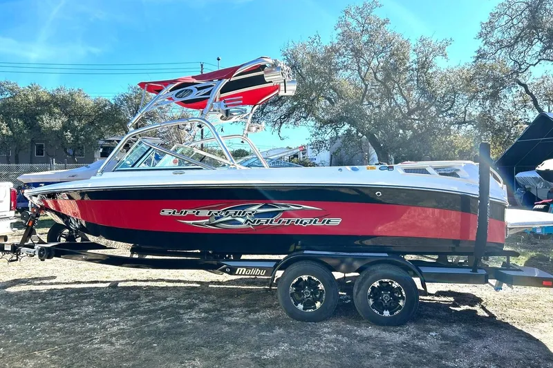 Slide: The Image of 2007 Nautique Super Air Nautique 220 boat on trailer, red and black design, outdoors. - 16