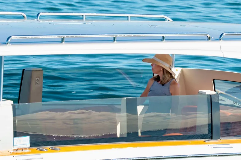 Slide: The Image of Woman in hat on 2016 Hodgdon Venetian boat, cruising on calm blue water. - 6