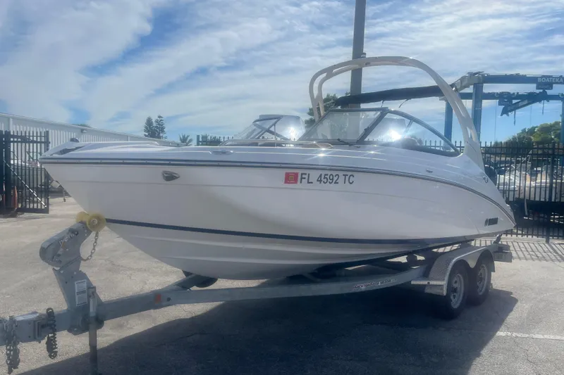 Slide: The Image of 2022 Yamaha Boats 212SE on trailer, parked outdoors under a partly cloudy sky. - 2