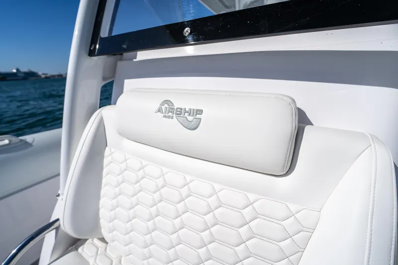 Slide: The Image of White leather seat on 2025 Airship 340 boat with embossed logo, ocean in background. - 25