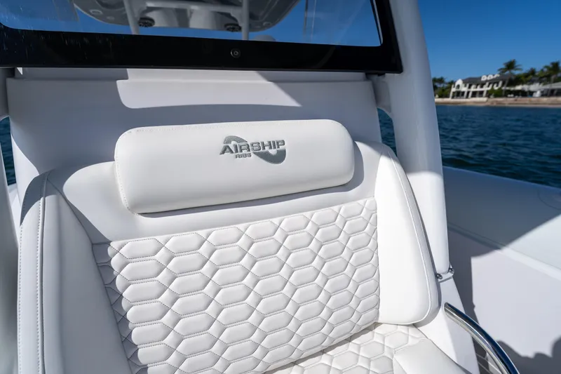Slide: The Image of Luxurious white seat on 2025 Airship 340 boat, featuring hexagonal stitching and logo. - 28