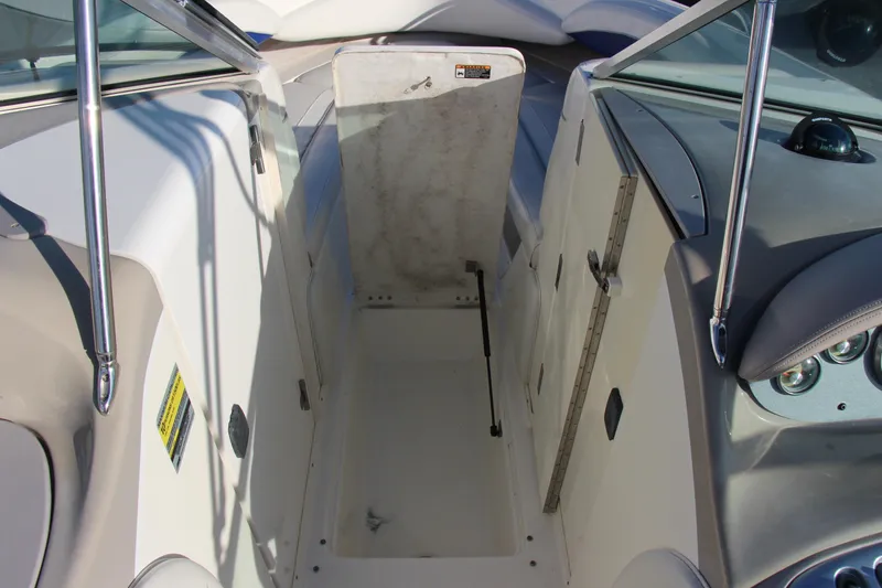 Slide: The Image of 2004 Maxum 2400 SR boat interior storage compartment with open hatch and visible dashboard. - 17