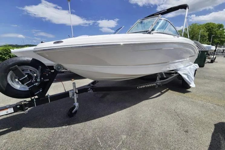 The Image of 2024 Chaparral 19 SSi OB boat on trailer, parked outdoors under blue sky. - 0