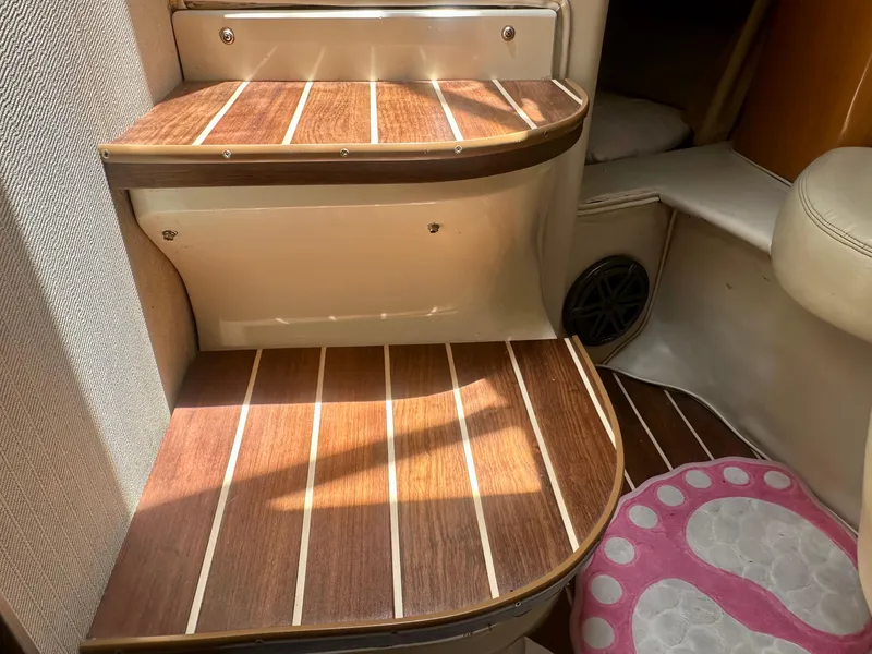 Slide: The Image of Wooden steps inside 2001 Regal Commodore 2760 boat, featuring striped design and pink foot-shaped mat. - 45