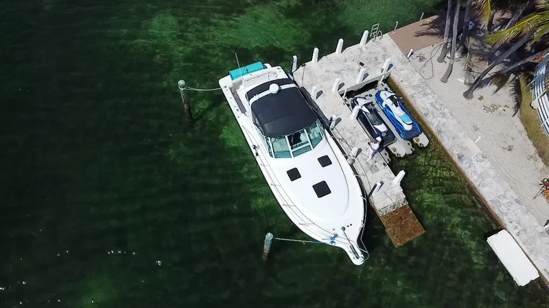 Slide: The Image of 2000 Tiara Yachts 3500 Open docked beside jet skis in clear water. - 1