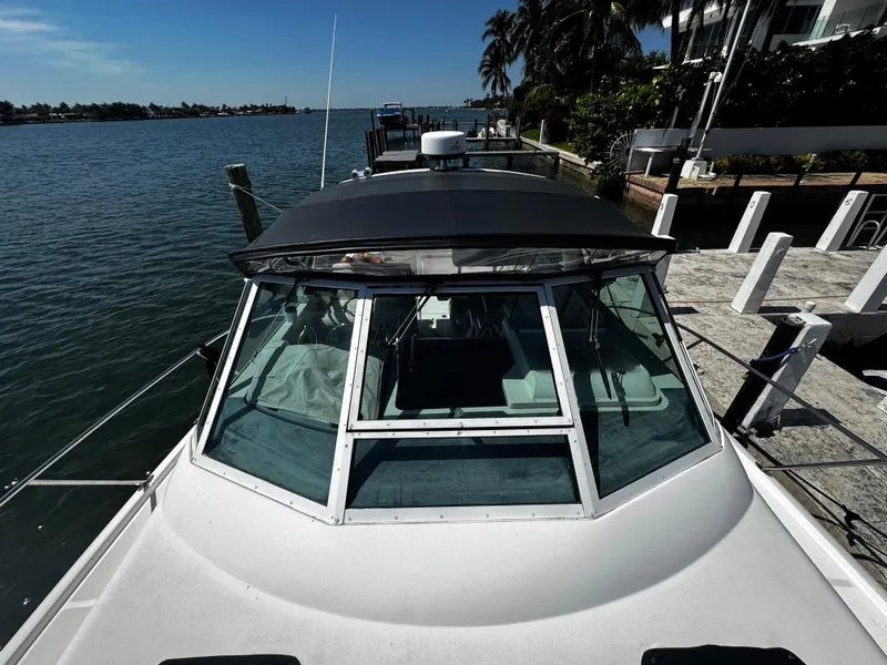 Slide: The Image of 2000 Tiara Yachts 3500 Open docked by a scenic waterfront with palm trees. - 30