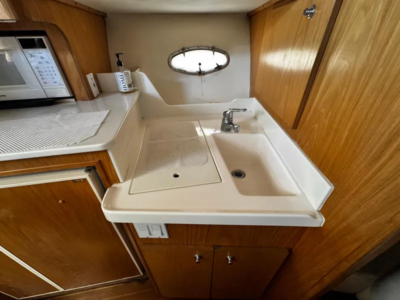 Slide: The Image of 2000 Tiara Yachts 3500 Open kitchen area with sink, wooden cabinetry, and microwave. - 37