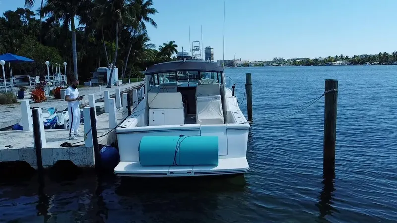 Slide: The Image of 2000 Tiara Yachts 3500 Open docked by a scenic waterfront with palm trees. - 8