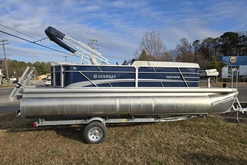 Slide: The Image of 2022 Godfrey Sweetwater 2286 BF pontoon boat on trailer, parked outdoors. - 2