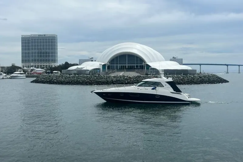 Slide: The Image of 2011 Sea Ray 450 Sundancer yacht cruising near modern waterfront architecture. - 3