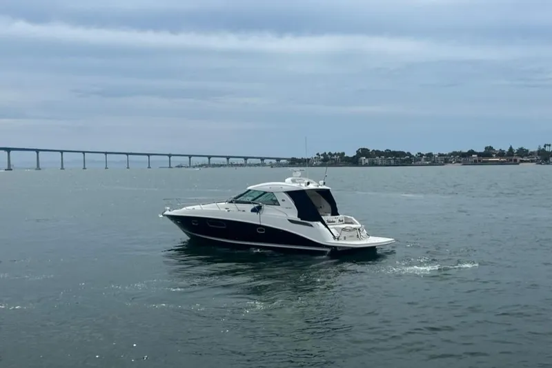 Slide: The Image of 2011 Sea Ray 450 Sundancer yacht cruising on calm waters near a bridge. - 46