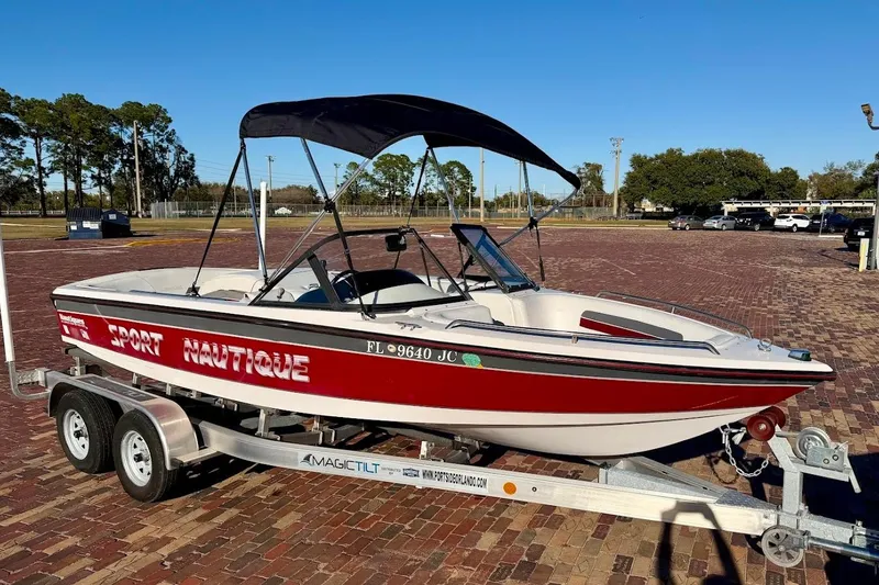 The Image of 1993 Correct Craft Sport Nautique boat on trailer, red and white design, parked outdoors. - 1