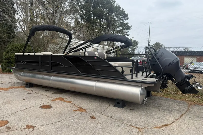 Slide: The Image of 2026 Bentley Pontoons Elite 253 Swingback with Suzuki outboard motor, parked outdoors. - 2