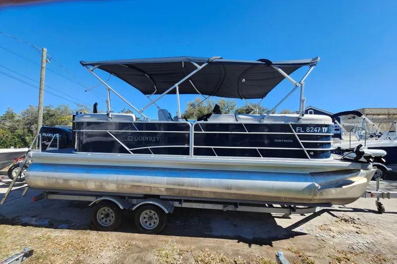 Slide: The Image of 2022 Godfrey Sweetwater 2286 SFL pontoon boat on trailer, featuring a black canopy. - 8