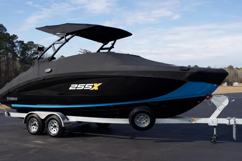 Slide: The Image of 2023 Yamaha Boats 255XD on trailer, covered, with sleek black and blue design. - 2